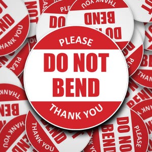 Könnte beinhalten: Nahaufnahme von mehreren roten und weißen runden Aufklebern mit der Aufschrift "Bitte nicht knicken Danke".