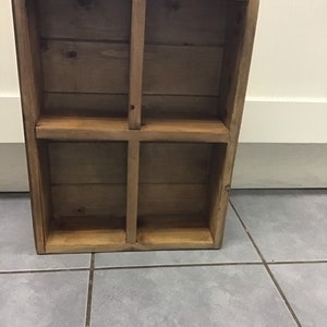 May include: A wooden shelf unit with four compartments. The shelf is made of natural wood with a light brown finish.