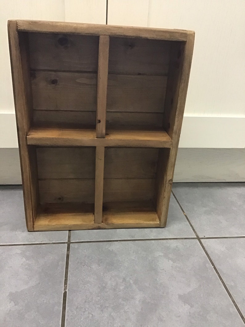 May include: A wooden shelf unit with four compartments. The shelf is made of natural wood with a light brown finish.