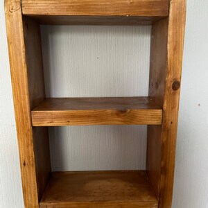 May include: A small wooden shelf with two shelves. The shelf is made of natural wood and has a rustic finish.