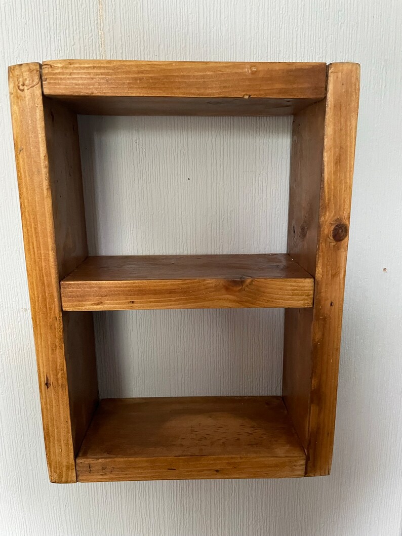 May include: A small wooden shelf with two shelves. The shelf is made of natural wood and has a rustic finish.