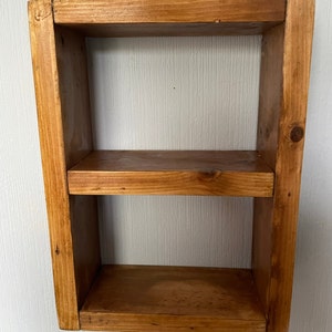 May include: A wooden shelf with two shelves. The shelf is made of natural wood and has a rustic look.