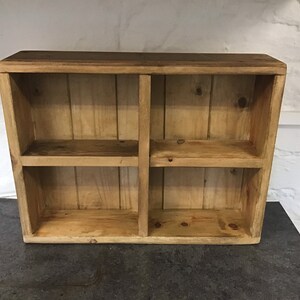 May include: A wooden shelf unit with four compartments. The shelf is made of natural wood with a rustic finish.