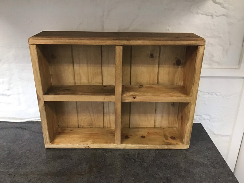 May include: A wooden shelf unit with four compartments. The shelf is made of natural wood with a rustic finish.