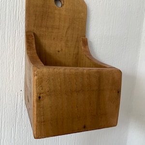 Pu&ograve; includere: Un contenitore rustico in legno da parete, con una parte superiore curva e un foro per appenderlo. La scatola a fronte aperto &egrave; realizzata in legno marrone chiaro, che mostra la venatura naturale. Il design &egrave; semplice e funzionale, adatto per riporre o esporre.