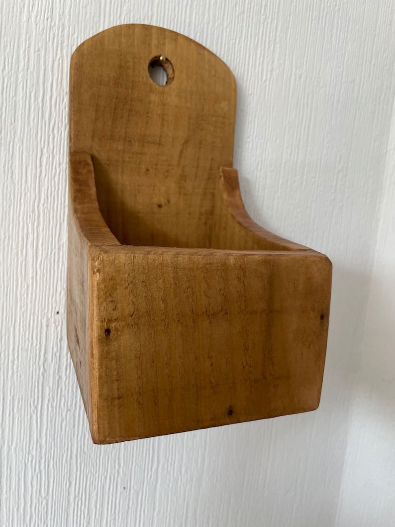 Pu&ograve; includere: Un contenitore rustico in legno da parete, con una parte superiore curva e un foro per appenderlo. La scatola a fronte aperto &egrave; realizzata in legno marrone chiaro, che mostra la venatura naturale. Il design &egrave; semplice e funzionale, adatto per riporre o esporre.