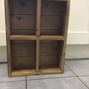 May include: A wooden shelf unit with four compartments. The shelf is made of natural wood with a light brown finish.