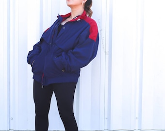 May include: A blue and red color block jacket with a zipper closure. The jacket has a stand-up collar and two pockets.
