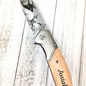 Op de afbeelding: Een zilveren zakmes met een houten handvat. Het lemmet is gegraveerd met een hert en het handvat is gegraveerd met de naam "Josiah".