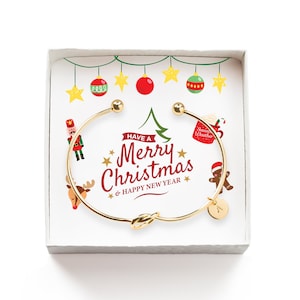May include: A gold-colored bracelet with a knot design, presented in a white gift box. The box features a festive Christmas-themed illustration with the text "Have a Merry Christmas & Happy New Year".