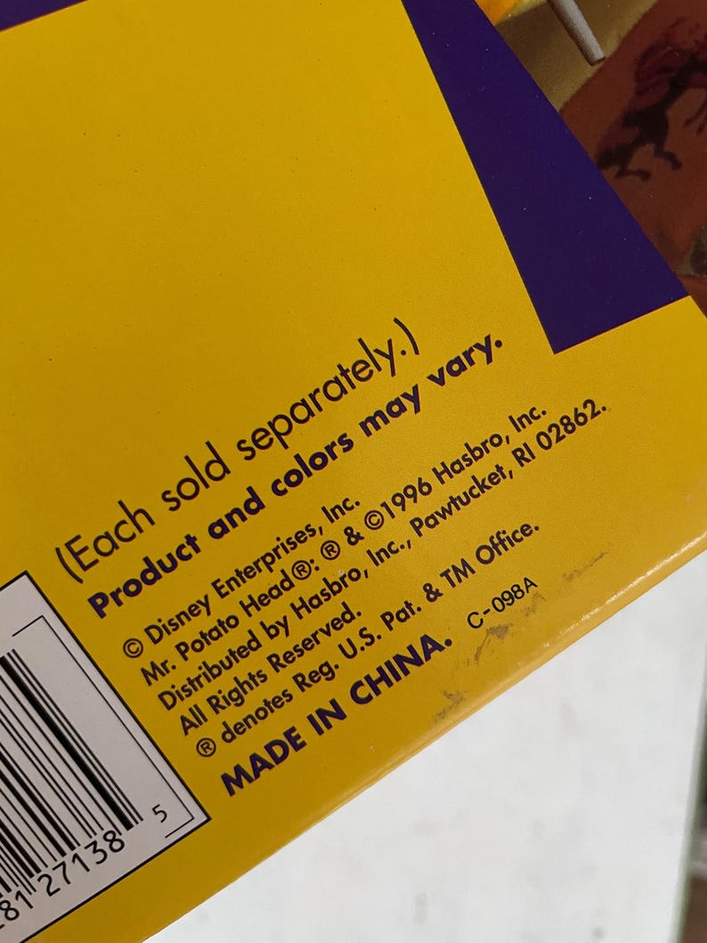 May include: Close-up of a yellow box with purple accents. Text includes "(Each sold separately.) Product and colors may vary." and copyright information for Disney Enterprises, Hasbro, and Mr. Potato Head. The box is marked "MADE IN CHINA."