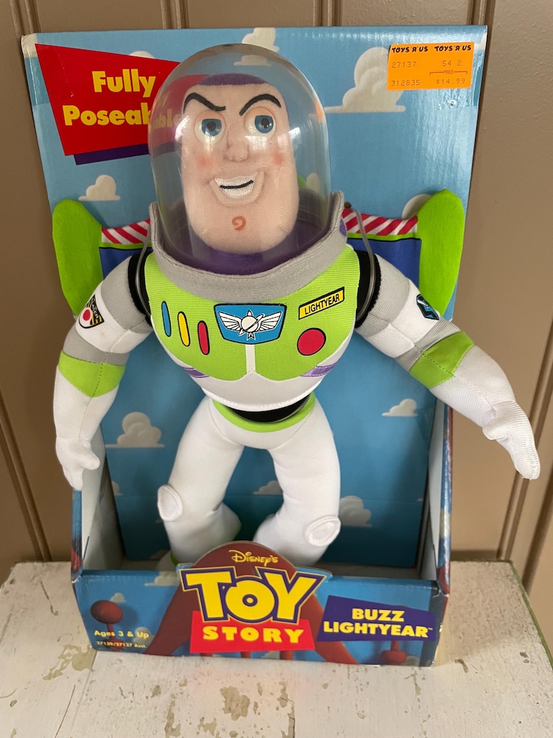 May include: Buzz Lightyear plush doll from Disney's Toy Story, in its original box. The doll features a white and green spacesuit, a clear helmet, and the words "Buzz Lightyear" on the box. The box also has the Toy Story logo.