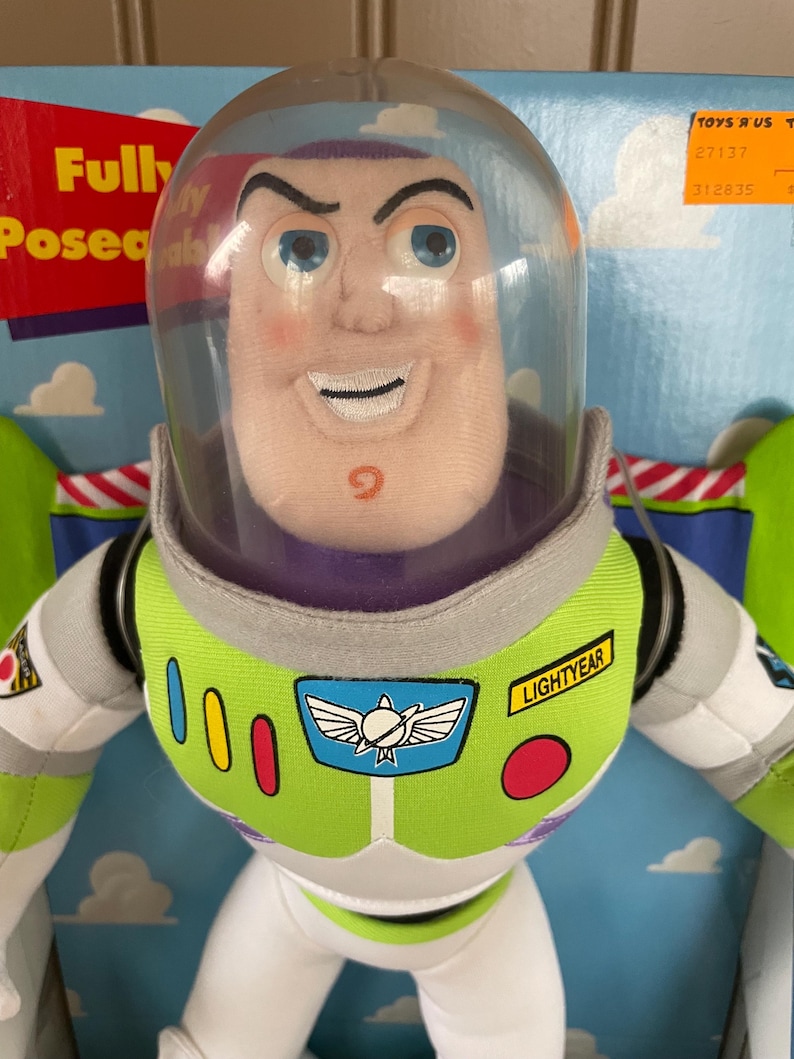 May include: Buzz Lightyear plush doll with a clear plastic helmet. The doll has a green and white spacesuit with the word "LIGHTYEAR" on the chest. The doll is in a box with the words "Fully Posed" visible.