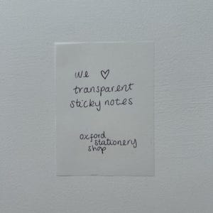 May include: A white note with black handwritten text that says "We &hearts; transparent sticky notes Oxford stationery shop".
