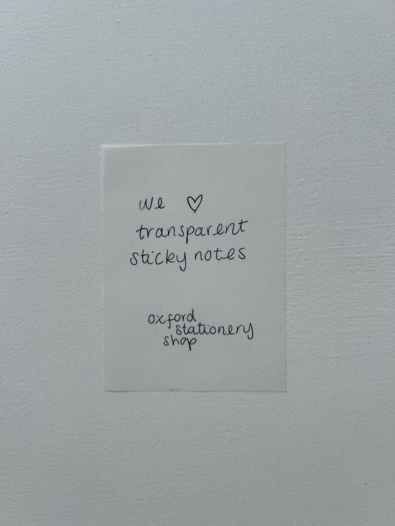 May include: A white note with black handwritten text that says "We &hearts; transparent sticky notes Oxford stationery shop".