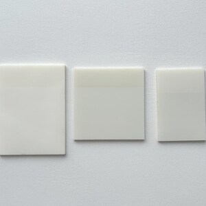 May include: Three white rectangular tiles, each with a slightly different shade of white.