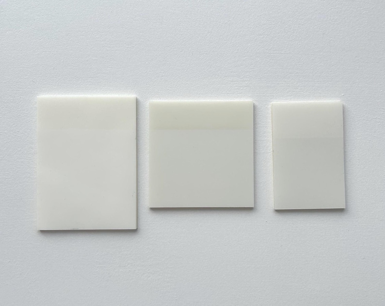May include: Three white rectangular tiles, each with a slightly different shade of white.