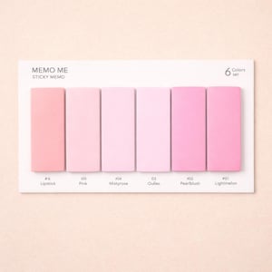 Pode incluir: Um conjunto de seis blocos de notas adesivas rosa em tons variados, rotulados com nomes de cores como "Lipstick" e "Lightmelon". Os blocos estão dispostos em um cartão branco com o texto "MEMO ME STICKY MEMO" e "6 Colors set."