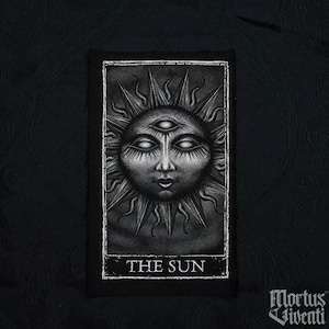 May include: Black and white tarot card patch with a detailed illustration of a sun with a human face and three eyes. The text "THE SUN" is printed below the image.