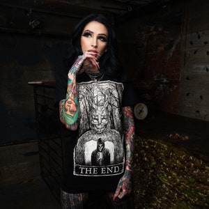 K&ouml;nnte beinhalten: Ein schwarzes T-Shirt mit einem wei&szlig;en Grafikdruck eines Wesens mit einem sch&auml;delartigen Gesicht und dem Text "THE END".
