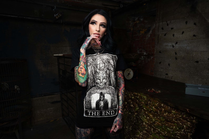K&ouml;nnte beinhalten: Ein schwarzes T-Shirt mit einem wei&szlig;en Grafikdruck eines Wesens mit einem sch&auml;delartigen Gesicht und dem Text "THE END".