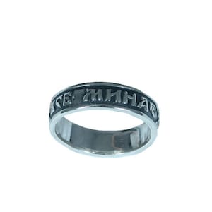 Può includere: Un anello d'argento con una fascia nera e un'iscrizione in una lingua antica.