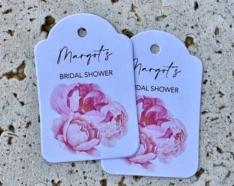 May include: Two white gift tags with a floral design. The text on the tags reads "Margot's Bridal Shower" and "Margot's Bridal Shower".