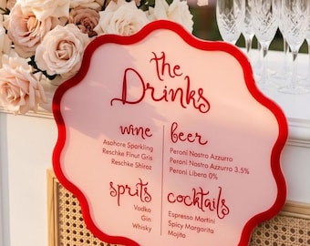 May include: A pink and red drinks menu with a wavy edge. The menu lists wine, beer, spirits, and cocktails. The text is in a cursive font. The background includes flowers and champagne flutes.