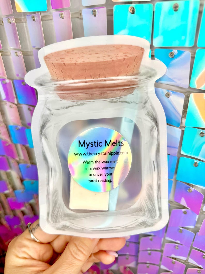 K&ouml;nnte beinhalten: Eine transparente, gl&auml;serne Verpackung mit einem Wachsschmelz und einem Korken. Die Verpackung tr&auml;gt ein Etikett mit der Aufschrift "Mystic Melts" und der Website-Adresse. Der Text auf dem Etikett besagt auch, dass man den Wachsschmelz in einem Wachsw&auml;rmer erw&auml;rmen soll, um Ihre Tarot-Lesung zu enth&uuml;llen.
