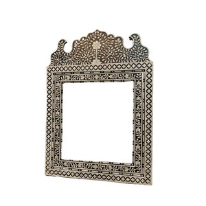 May include: A black and white ornate mirror frame with intricate floral designs. The frame is made of wood and has a raised, arched top.