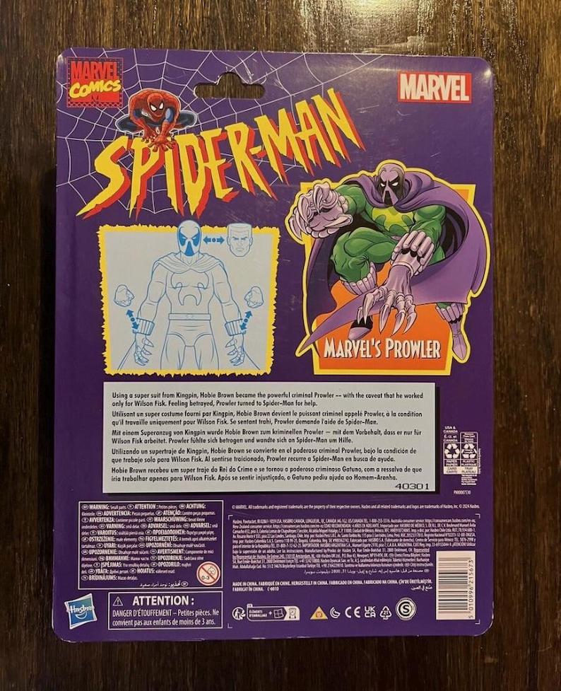 May include: Back of a Marvel Comics Spider-Man action figure package featuring the Prowler. The package is purple and features a cartoon image of the Prowler in his green and purple suit. The text on the package reads "Marvel's Prowler".