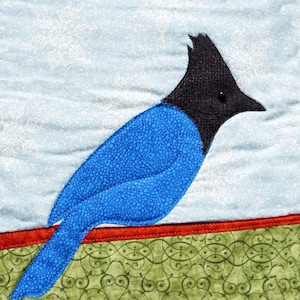 Può includere: Un uccello blu e nero con una lunga coda, appollaiato su un tessuto con motivi rossi e verdi. L'uccello è una rappresentazione stilizzata di un ghiandaia azzurra.