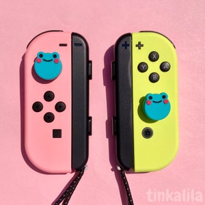 Pode incluir: Dois controladores Nintendo Switch Joy-Con com bot&otilde;es personalizados em forma de sapo. O controlador esquerdo &eacute; rosa e o controlador direito &eacute; amarelo.