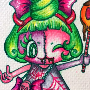 Op de afbeelding: Een aquarelillustratie van een roze en groen cartoonfiguur met een groene werveling op zijn hoofd, die een zwarte jurk draagt met een spinnenwebpatroon, een roze strik en een ketting met een roze schedel en een hartstrik. Het figuur houdt een lolly met een rood-wit gestreepte stok.