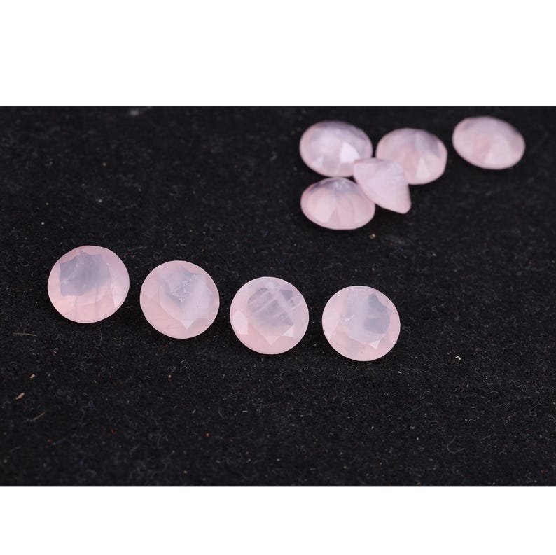 Puede incluir: Colecci&oacute;n de gemas facetadas de color rosa p&aacute;lido. Las gemas son redondas con una parte posterior plana y una parte superior multifac&eacute;tica. Las gemas est&aacute;n dispersas sobre una superficie negra, algunas agrupadas y otras espaciadas.