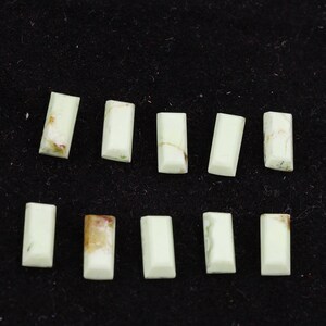 May include: Ten rectangular green and white gemstone cabochons, arranged in two rows of five. The cabochons are smooth and polished.