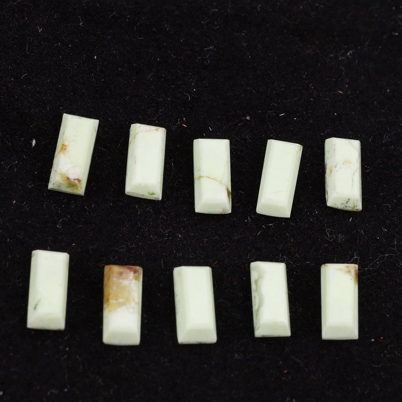 May include: Ten rectangular green and white gemstone cabochons, arranged in two rows of five. The cabochons are smooth and polished.