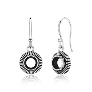 May include: A pair of silver-toned earrings. Each earring features a circular design with a black center and a detailed, ridged outer edge. The earrings have a hook closure.