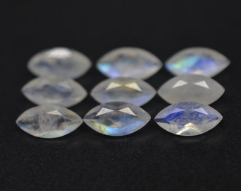 Puede incluir: Ocho piedras preciosas de piedra lunar de forma marquesa con colores iridiscentes azules y blancos. Las piedras están dispuestas en dos filas de cuatro.