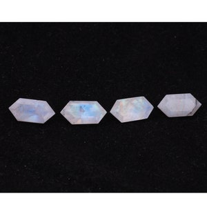May include: Four iridescent moonstone gemstones, each cut into a hexagonal shape with rounded edges. The stones are a pale white with a subtle blue sheen.