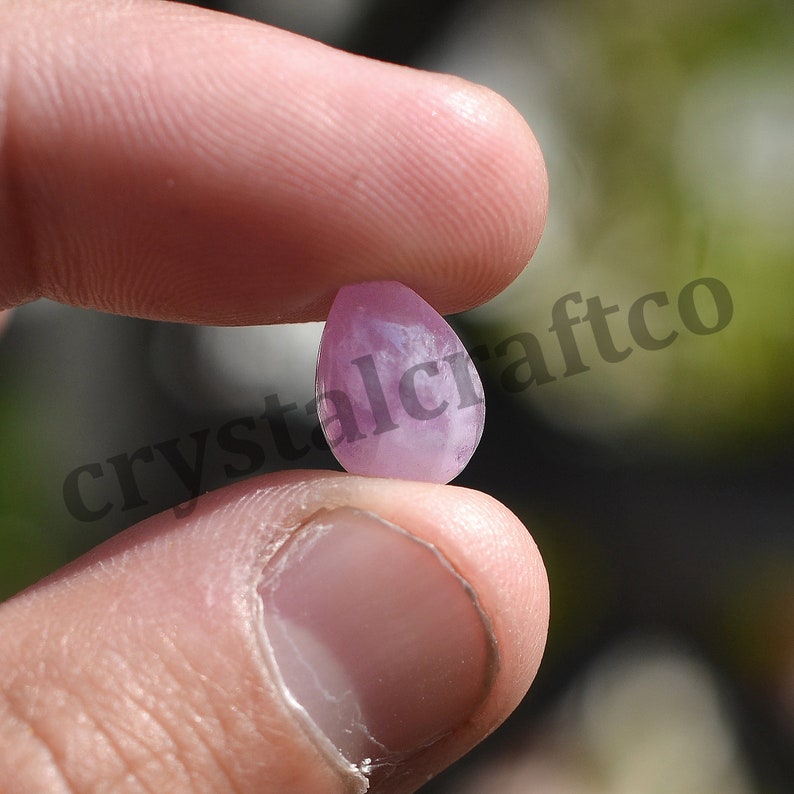 May include: A teardrop-shaped, light pink gemstone with a smooth, polished surface.