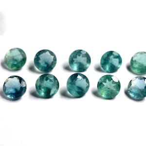 May include: Ten round, faceted, blue-green gemstones. The gemstones are arranged in two rows of five.