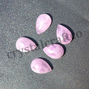 May include: Five pink teardrop shaped gemstone cabochons. The stones are smooth and polished.