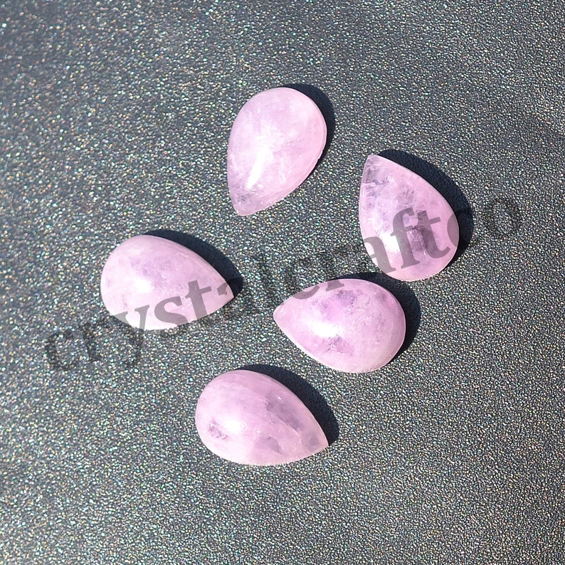 May include: Five pink teardrop shaped gemstone cabochons. The stones are smooth and polished.