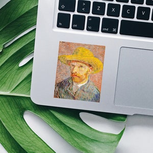 May include: A sticker featuring a portrait of Vincent van Gogh in a yellow hat. The artwork is a close-up of the artist's face, with visible brushstrokes and a textured appearance. The sticker is placed on a laptop.