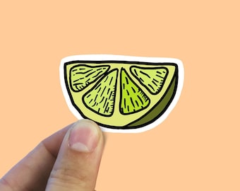 May include: A lime wedge sticker with a white border. The lime is green and yellow and has a detailed drawing of the segments.
