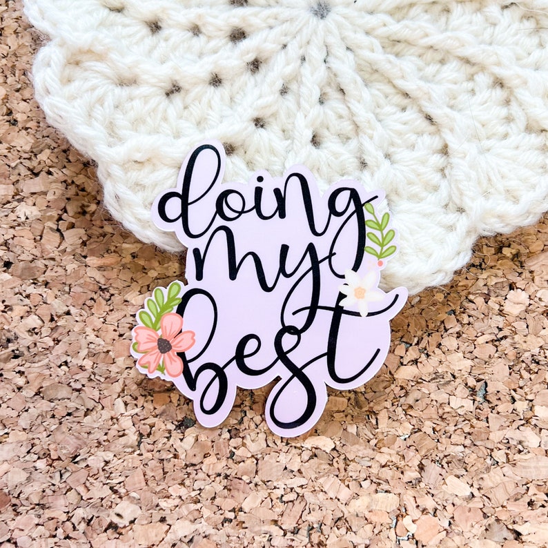 May include: A sticker with a light purple background and black text that reads "doing my best". The sticker has a floral design with pink and green flowers.