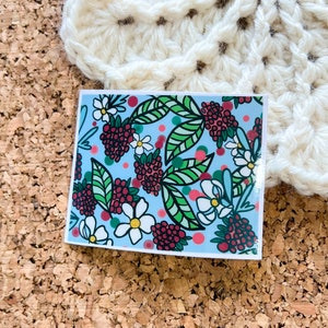 May include: A sticker with a repeating pattern of red berries, white flowers, and green leaves on a light blue background.
