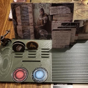 May include: A green plastic game board with a character miniature, tokens, and cards. The cards feature text such as "Witch Hunter" and "Cursed".