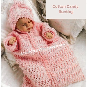 以下が含まれることがあります： ピンクのクロシェ編みベビーバントリングとそれに合わせた帽子。バントリングはテクスチャのあるステッチでできており、前面にジッパーが付いています。帽子には、クロシェ編みの花が飾られています。バントリングは白い表面に置かれています。